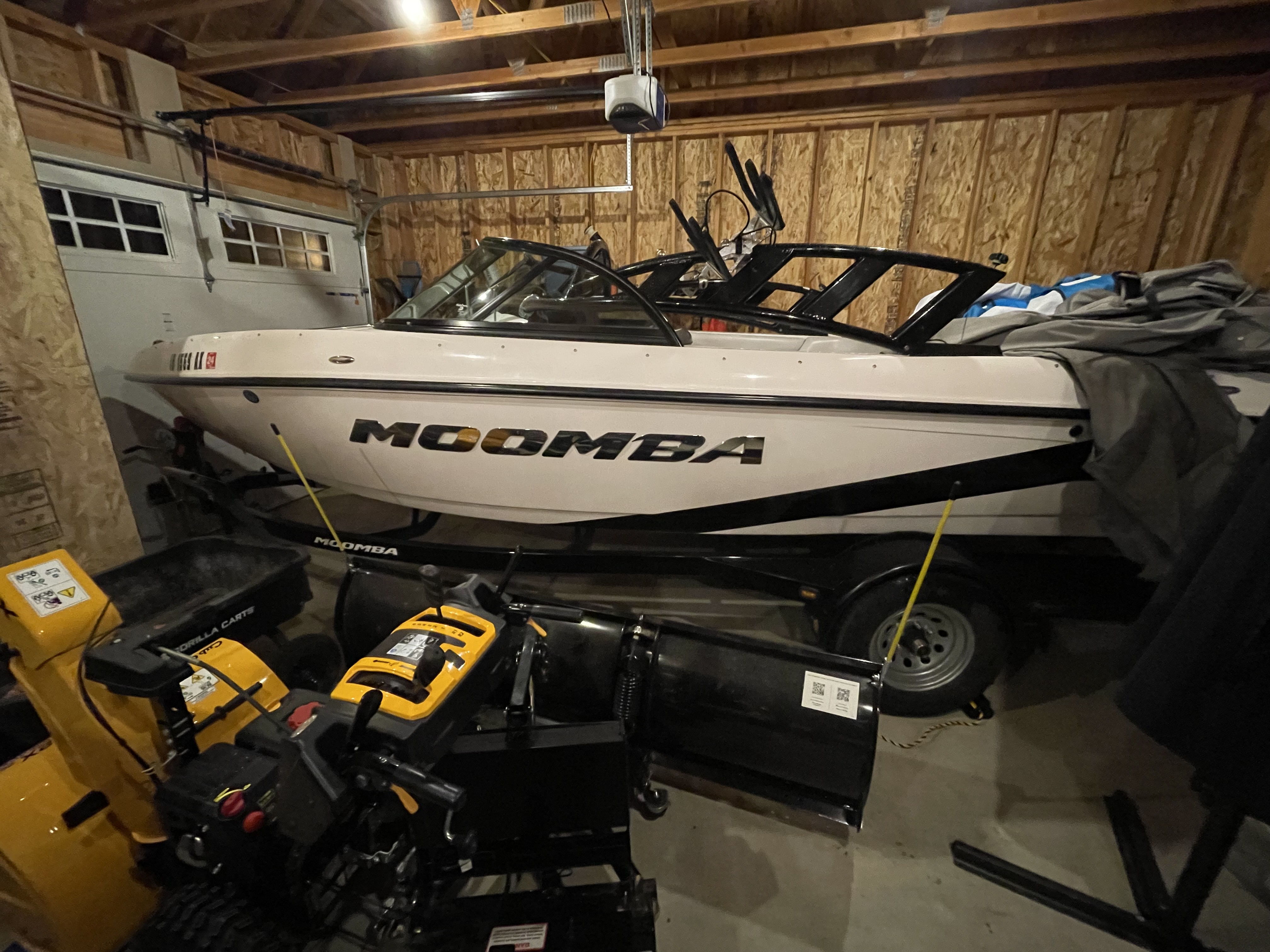 Our boat in the garage with a snowblower and snow plow in the foreground